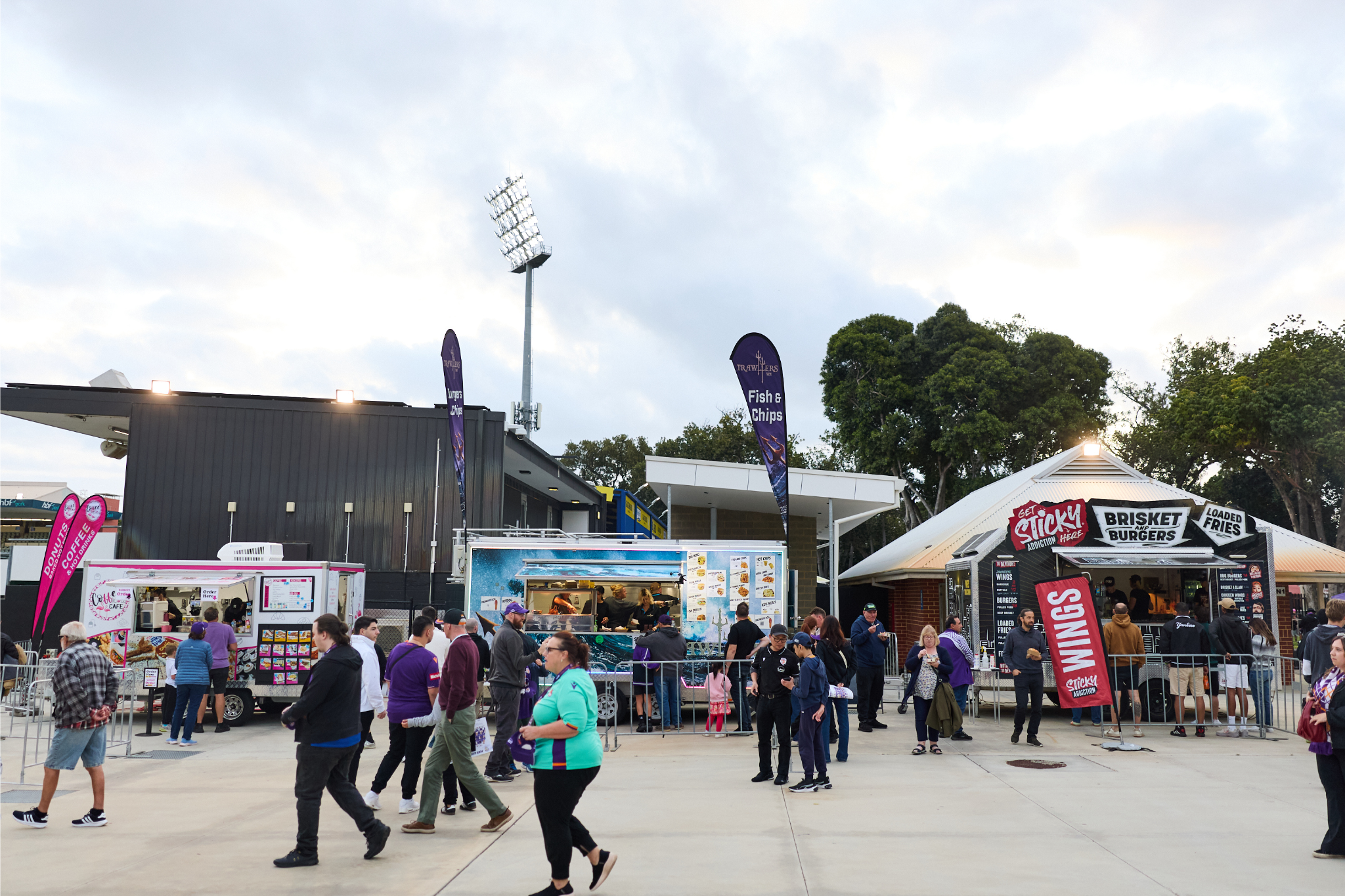 A photo of multiple people food and drinks under some marquees at HBF Park