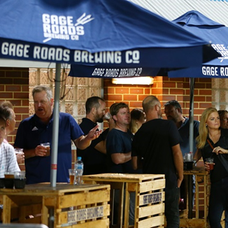 A photo of multiple people food and drinks under some marquees at HBF Park